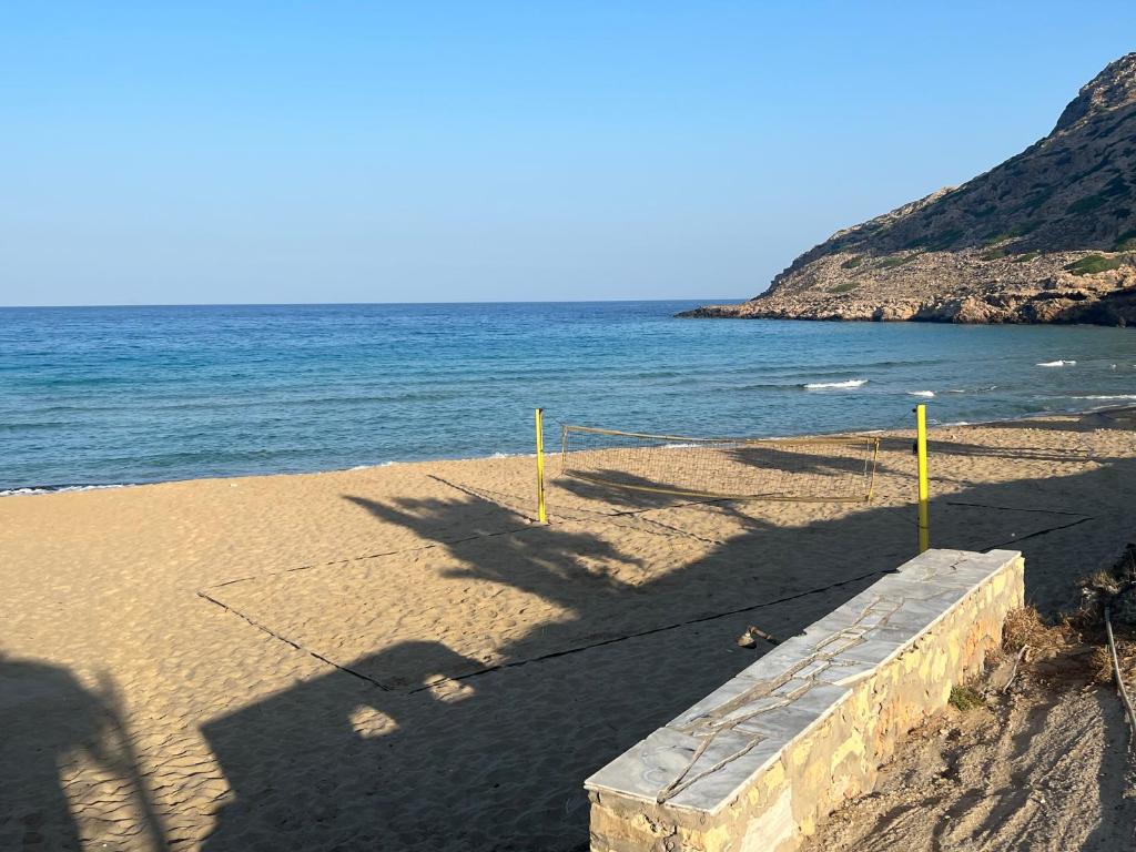 a beach with yellow poles in the sand and the ocean at Royal Beach Hotel in Arkasa