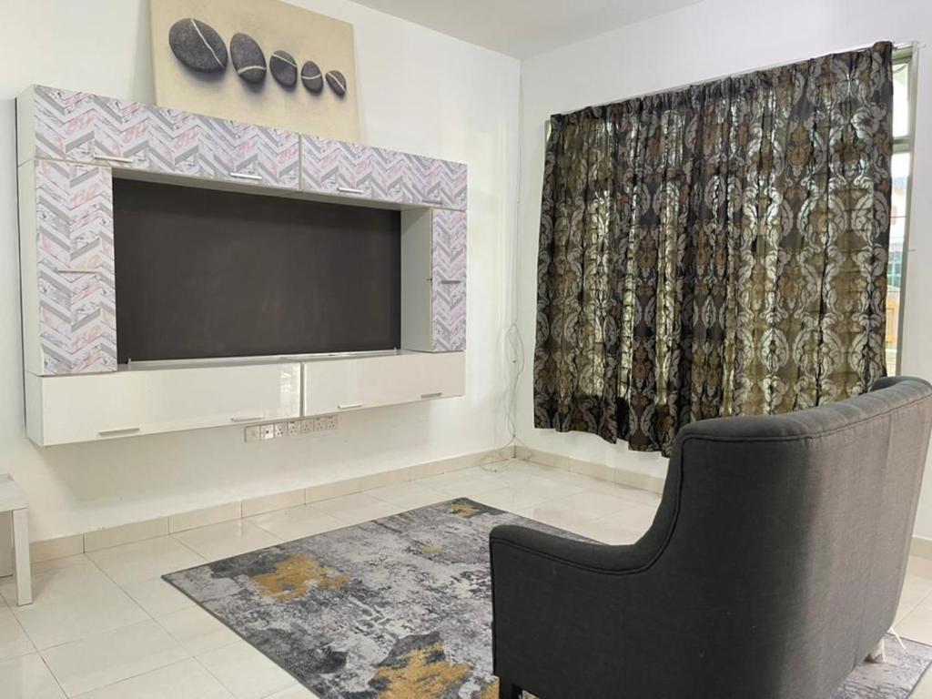 a living room with a flat screen tv and a chair at Homestay Merbau Changloon in Changlun