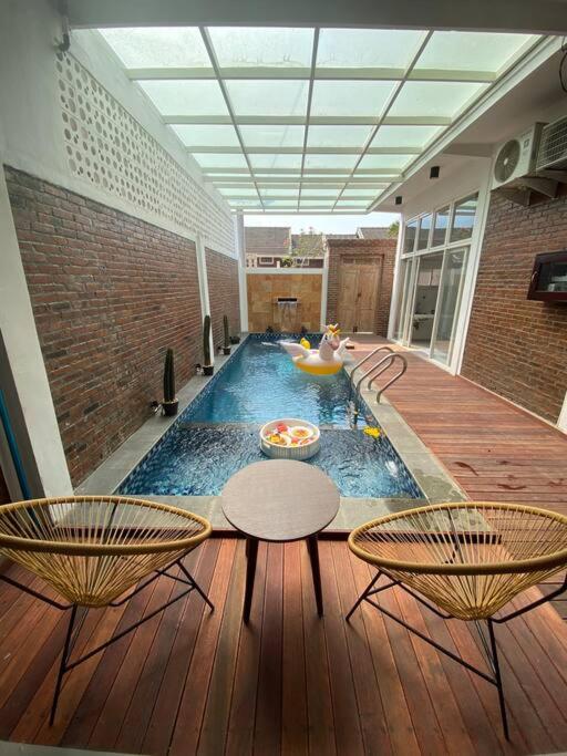 a large pool in a building with chairs and tables at Emka Family Villa Malang in Malang