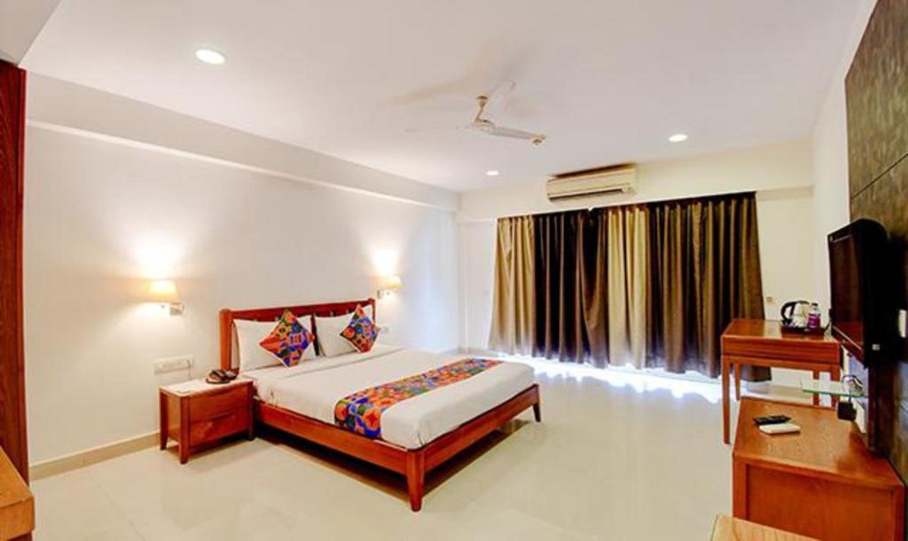 een slaapkamer met een bed, een bureau en een televisie bij FabHotel Prime Indeedcare Hotel & Resorts in Jojera