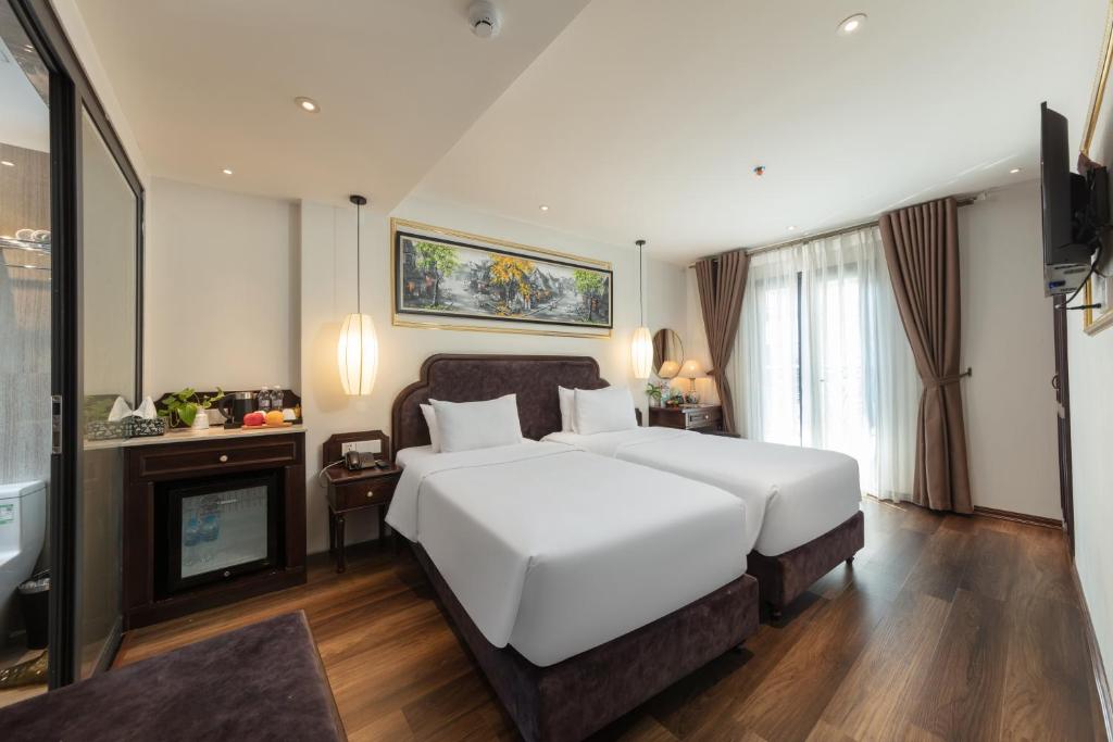 a bedroom with a large white bed and a fireplace at Hanoi Calista Hotel in Hanoi