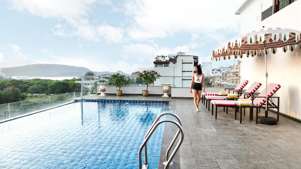 una donna che cammina sul balcone di un hotel con piscina di Hotel Bawa Udaipur a Udaipur