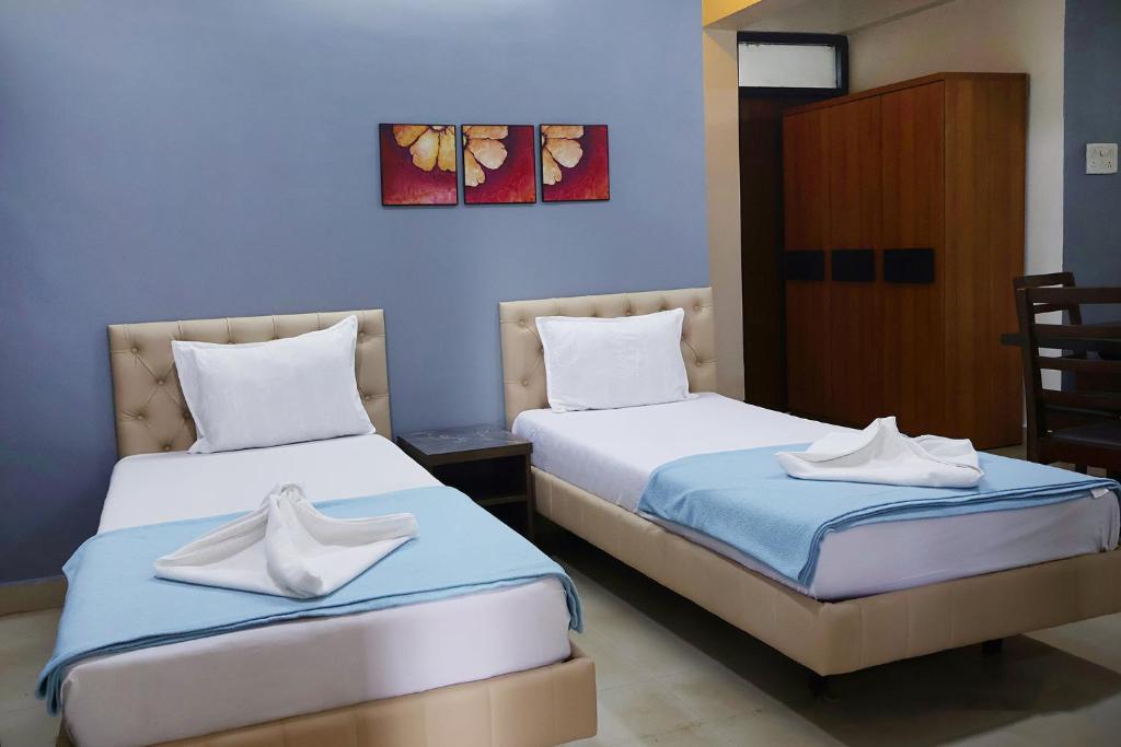 a room with two beds with white shoes on them at FabEscape Orient Royal in Calangute