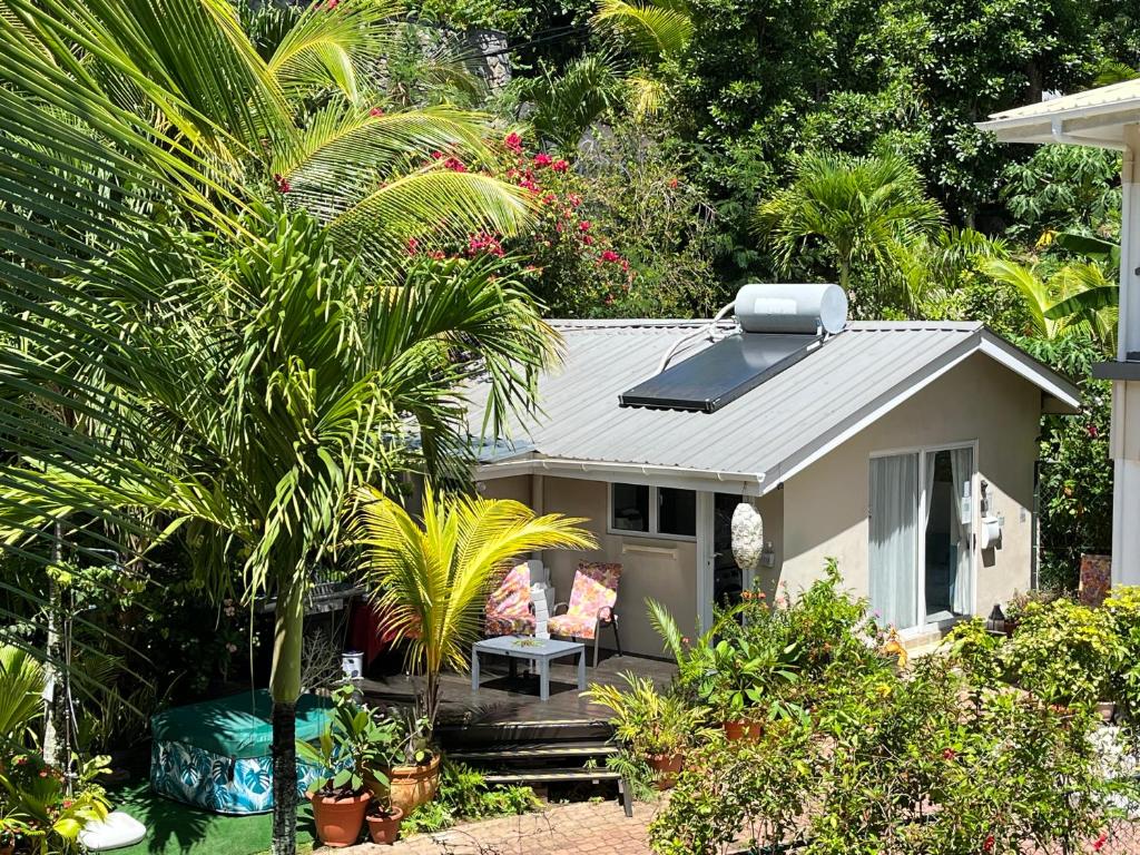 a small house with a porch and palm trees at Royal Bay Apartment in Anse Royale