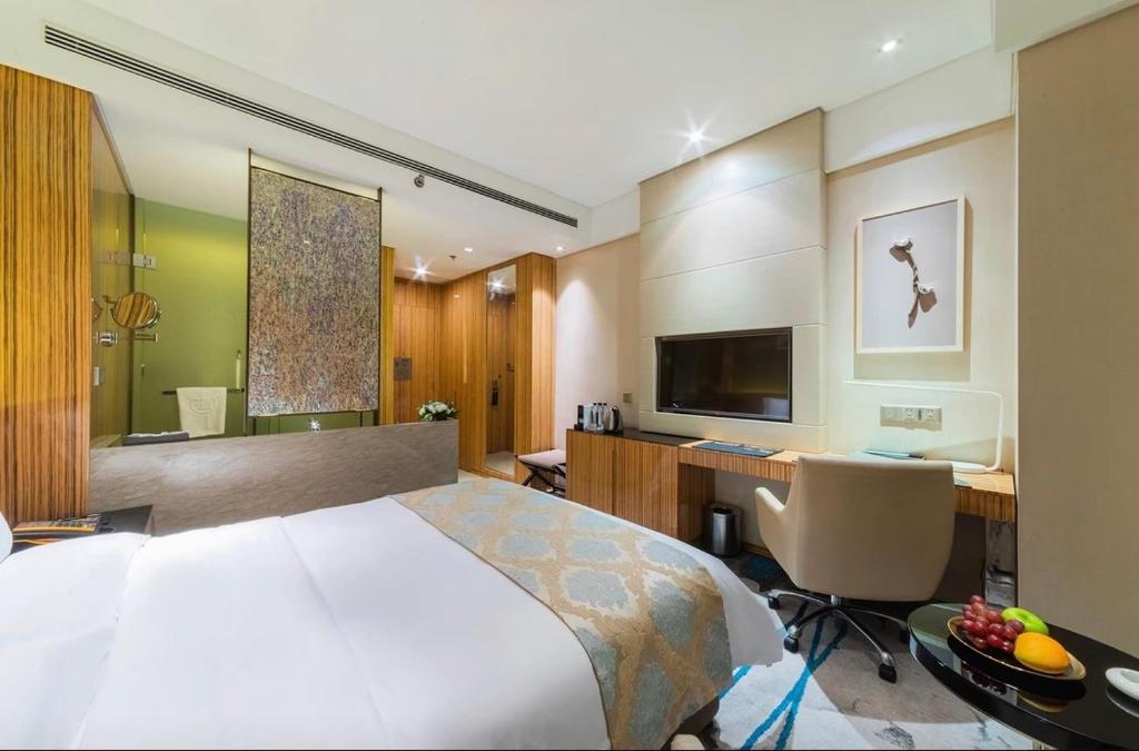 Yinchuan Xifujing Hotel في ينشوان: غرفة في الفندق بها سرير ومكتب وبه جهاز كمبيوتر
