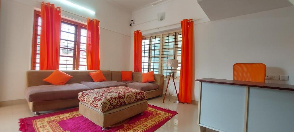 a living room with a couch and orange curtains at Orange Valley Homestay Trivandrum in Trivandrum