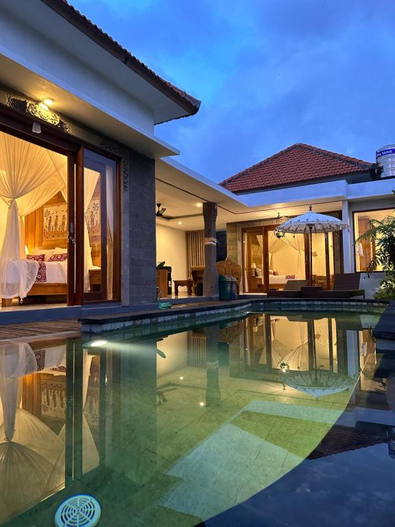 a villa with a swimming pool at night at Gyanesh Villa in Ubud