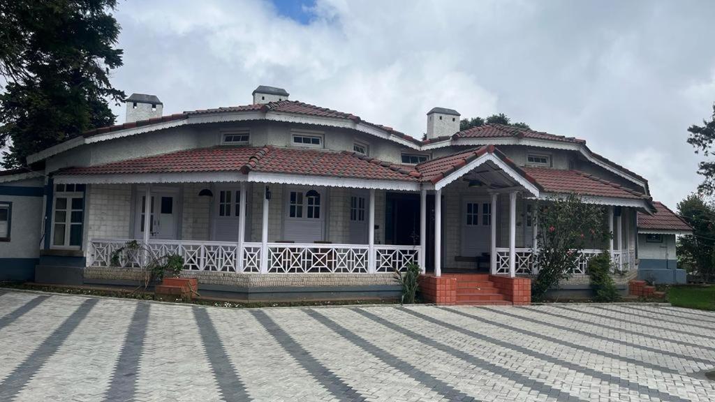 a large white house with a driveway in front of it at Bruton resorts in Kodaikānāl