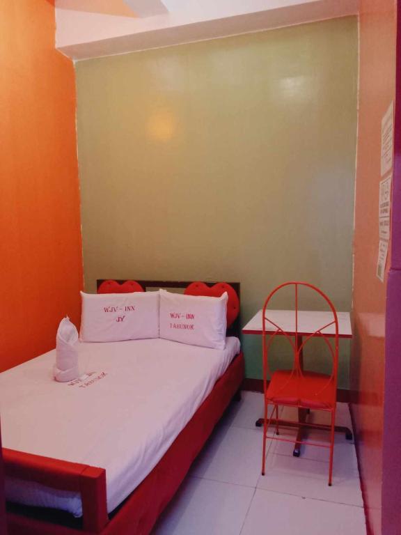 a small room with a bed and a red chair at WJV INN TABUNOK in Talisay