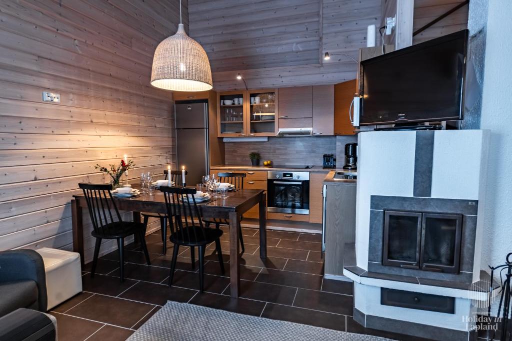 a kitchen and dining room with a table and a fireplace at Holiday in Lapland - Ellenpolku 2 K2 in Ylläs