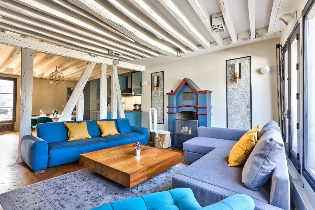 ein Wohnzimmer mit blauen Sofas und einem Holztisch in der Unterkunft Le Marais Superb Apartment Terrace Paris in Paris