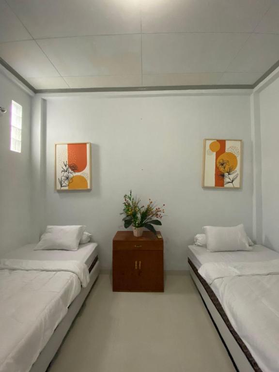a room with two beds and a table with a plant at Lorent Hostel Near Padang Beach in Padang