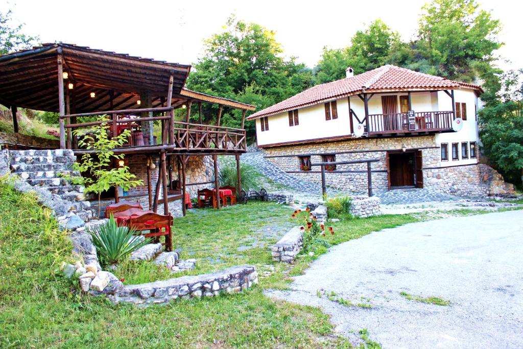 a house with a porch and a building with a balcony at Melnik Pyramids Guesthouse in Zlatkov Chiflik