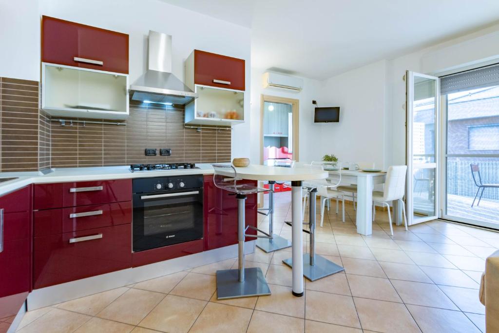 a kitchen with red cabinets and a table in it at Appartamento L'Approdo Trilo Rosso - MyHo Casa in Marina di Montenero