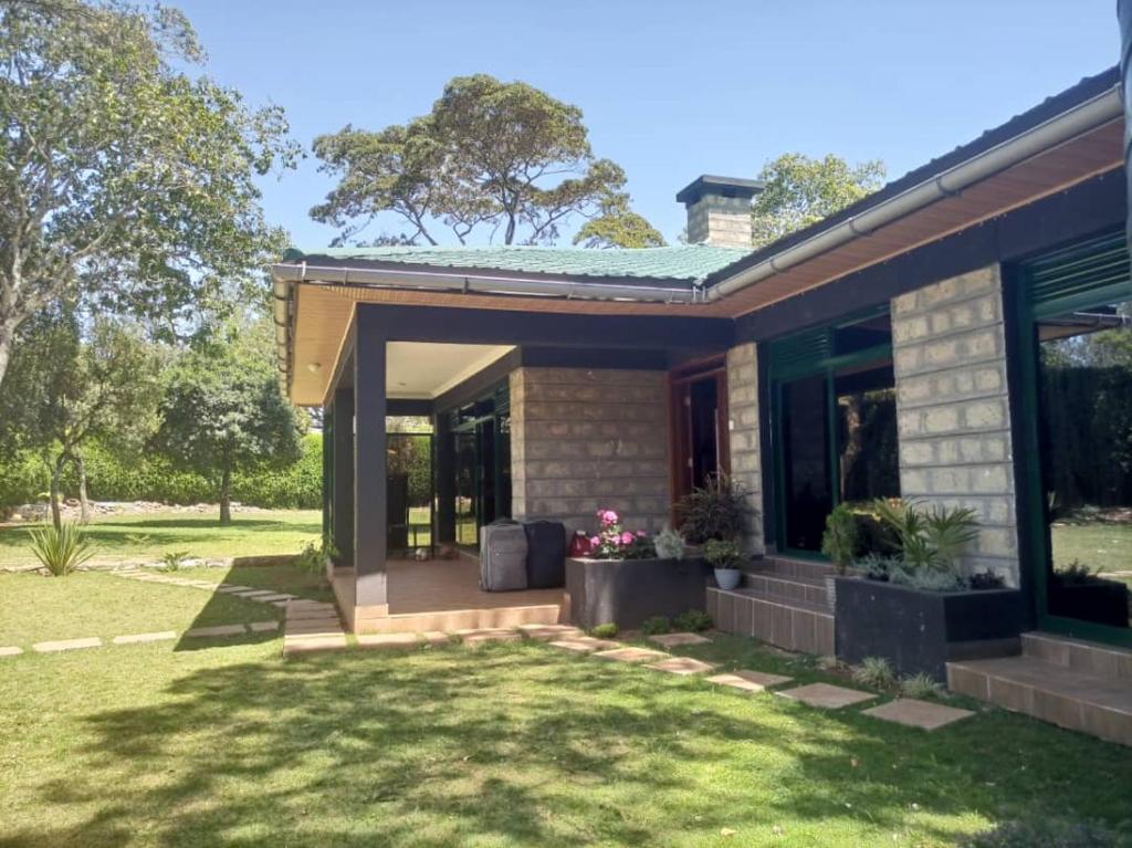 a house with a porch and a grass yard at Cozy Karen in Nairobi