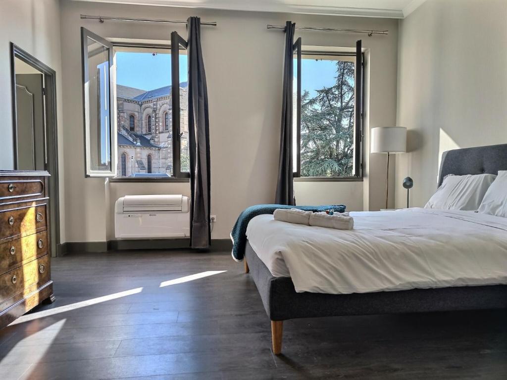 une chambre avec un grand lit et deux fenêtres dans l'établissement Le Coté Jardin - Fibre - Clim - Centre-ville, à Albi