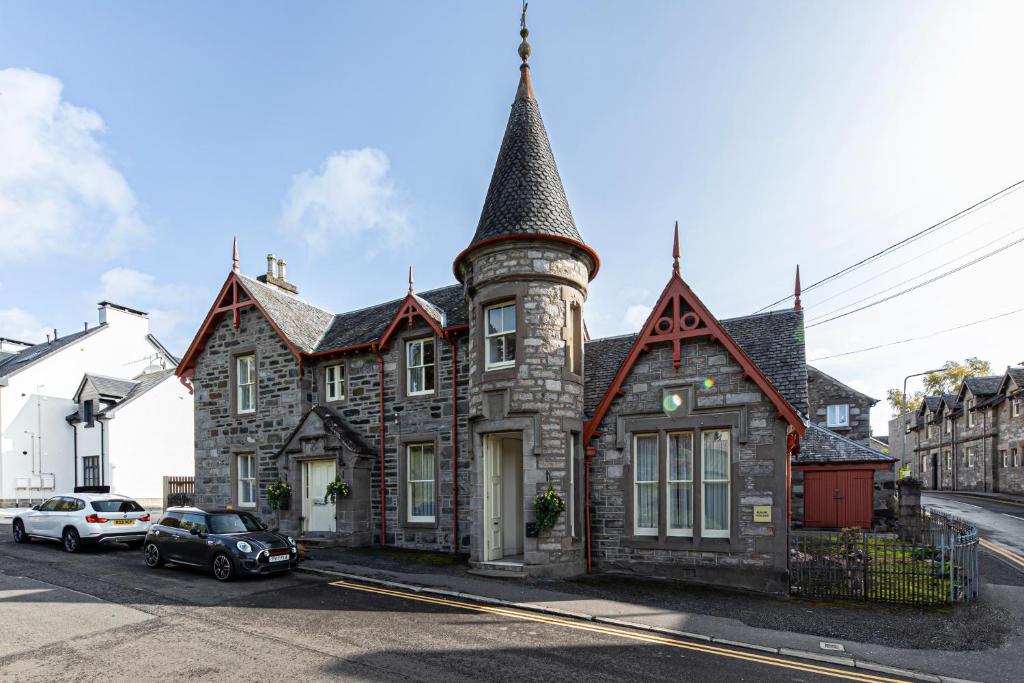 uma antiga casa de pedra com uma torre numa rua em The Bank House at Scotland's Hotel em Pitlochry