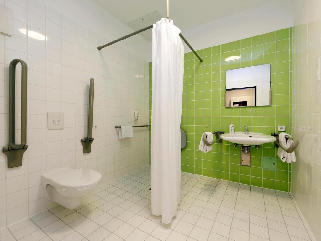 - une salle de bains verte et blanche avec toilettes et lavabo dans l'établissement B&B Hotel Berlin-Tiergarten, à Berlin