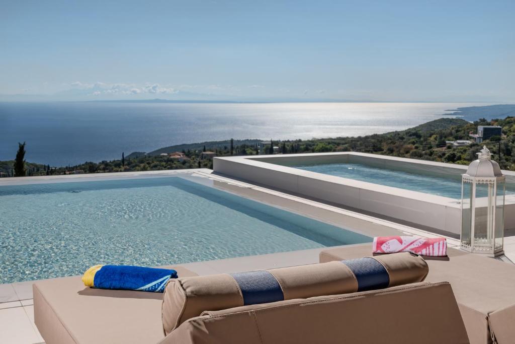 einen Pool mit Stühlen und Blick auf das Wasser in der Unterkunft Archontiko Stoufi in Skinária