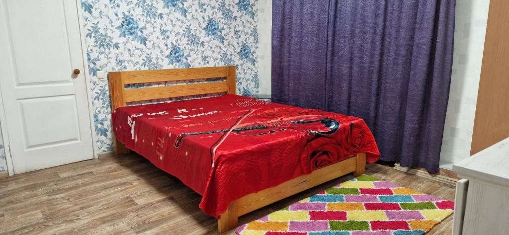 a bedroom with a bed with a red blanket and a rug at Yanovskogo 1k Shin in Kropyvnytskyi