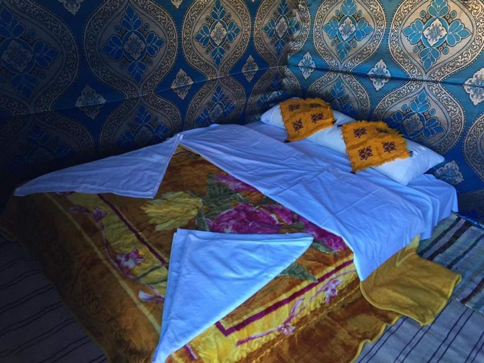 a bed with a blue comforter and pillows at Honeymoon Luxury Glamping in Adrouine