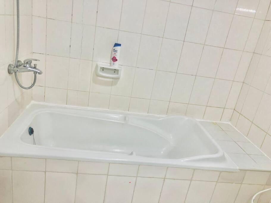 a bath tub in a tiled bathroom with a shower at Private Room in Dubai-Sharjah Border in Sharjah