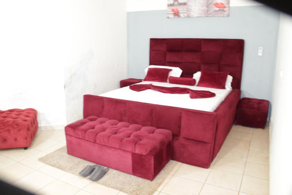 a bedroom with a red bed and a red couch at KRISTAL HOME in Yaoundé