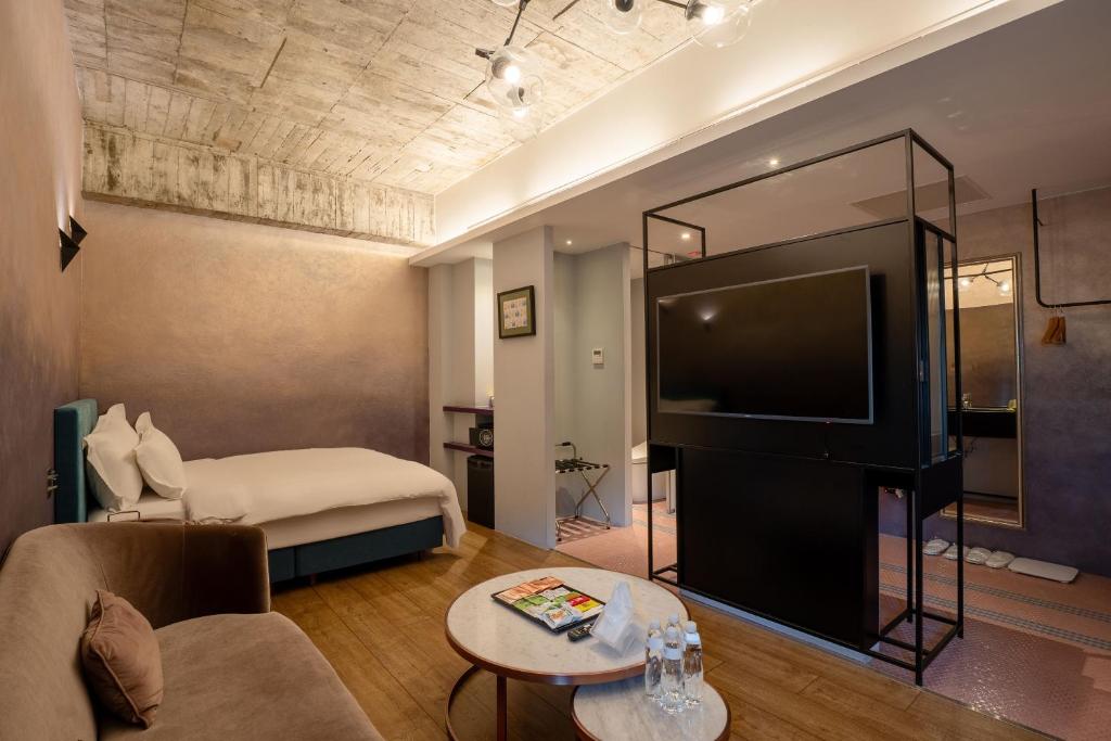a hotel room with a bed and a large television at CHECK inn HIVE in Luodong