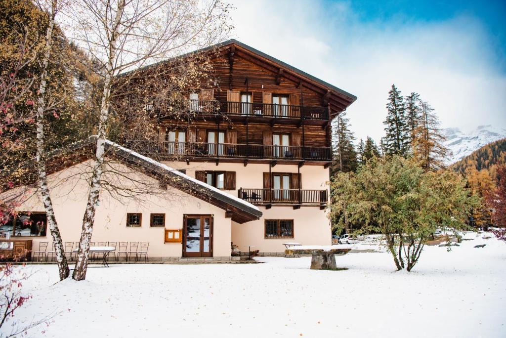 a building in the snow with a bench in front at Alpine Forest Hotel in Champoluc