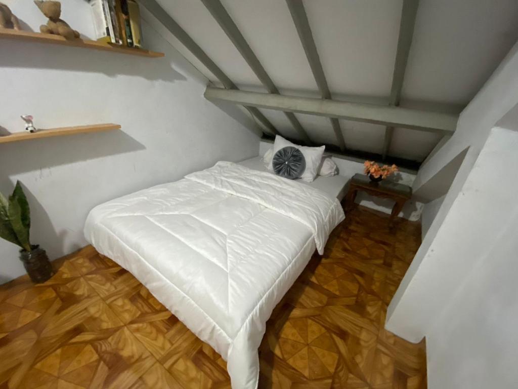 a bedroom with a white bed in a attic at Lorent Hostel Near Padang Beach in Padang