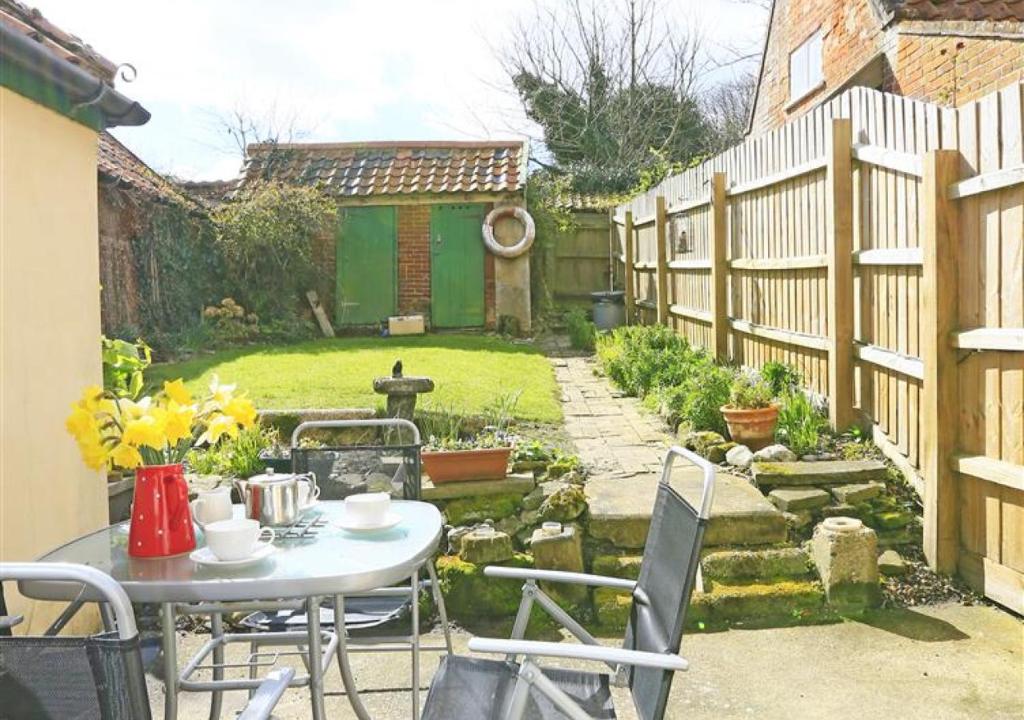 a garden with a table and chairs and a fence at Tinkers Cottage in Dunwich