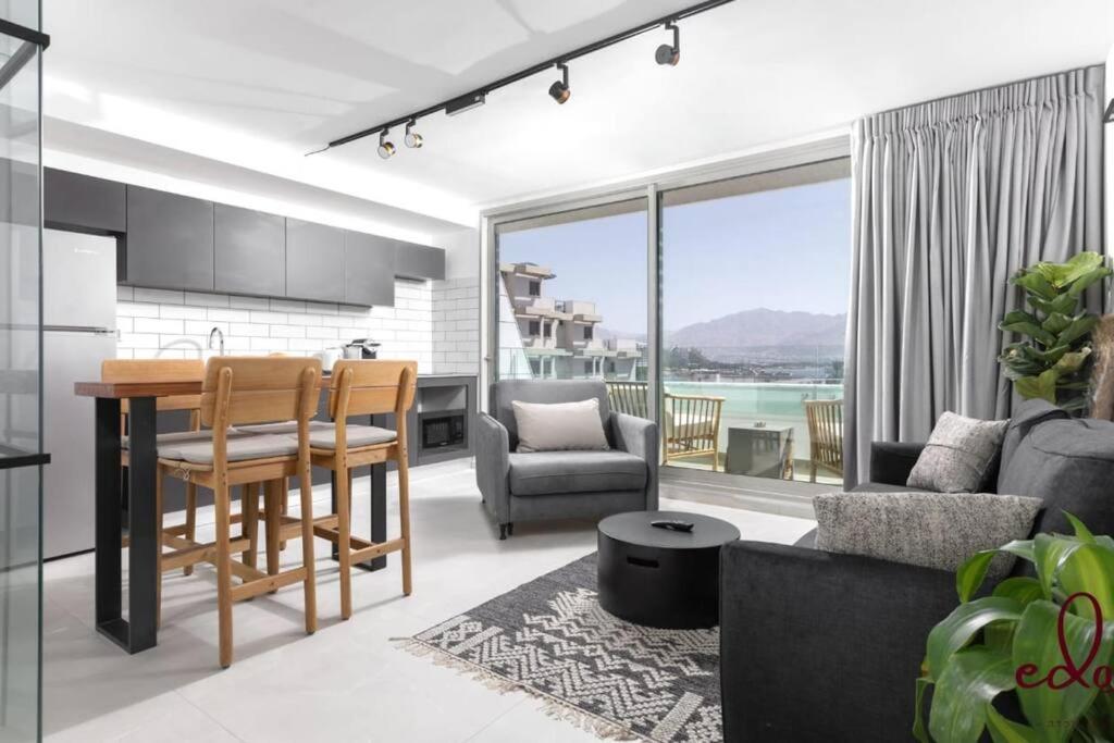 a kitchen and living room with a table and chairs at דירת חדר שינה וסלון 50 מטר מהים - By Edomlux in Eilat