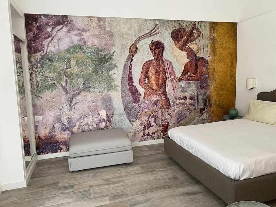 ein Schlafzimmer mit Wandgemälde und einem Bett in der Unterkunft Soggiorno tra storia e design la Domus in Ercolano