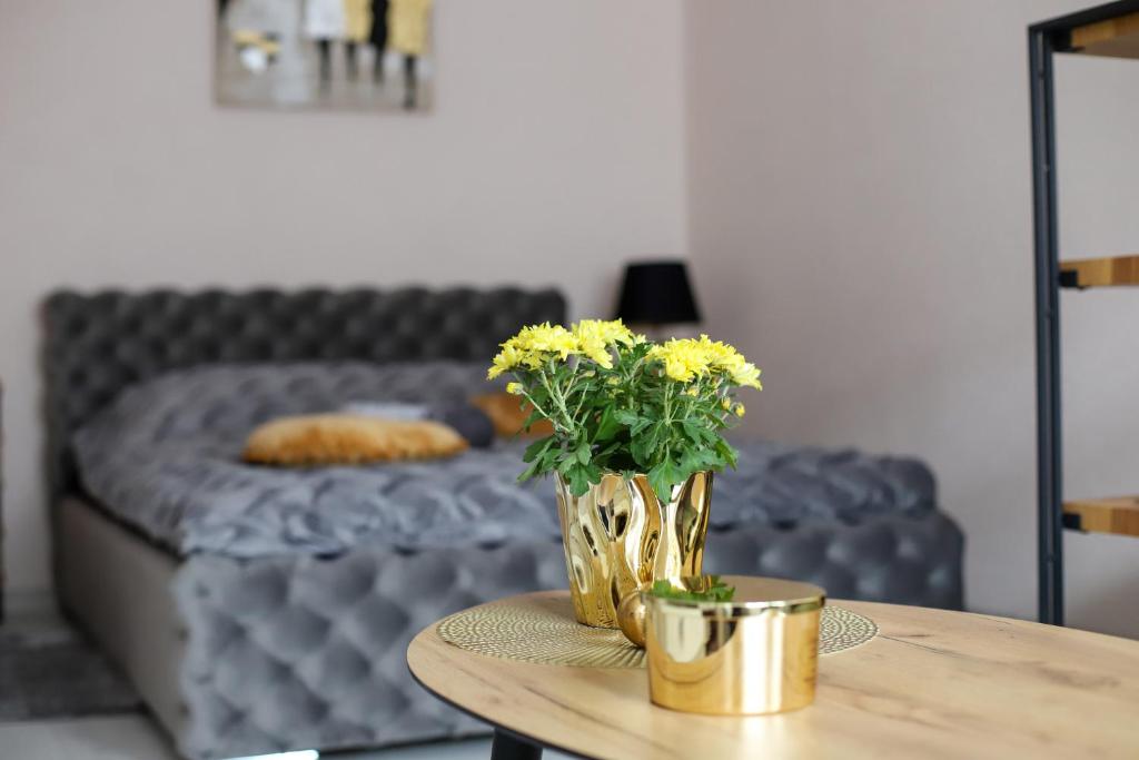 a table with a vase with yellow flowers on it at Dzintara apartamenti in Kuldīga