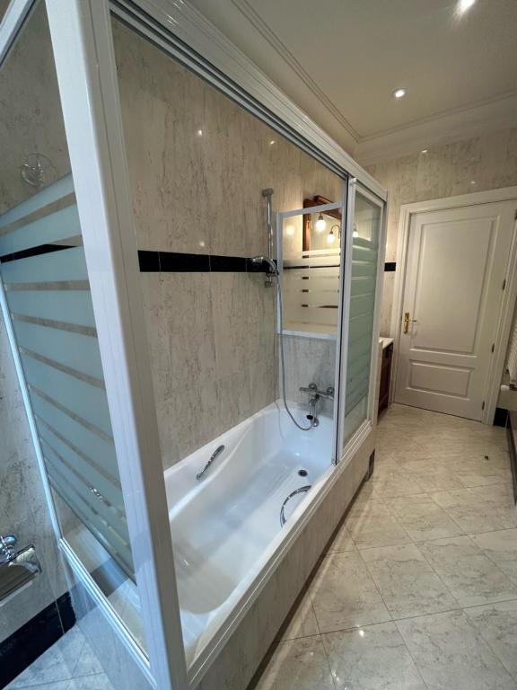 a large bathroom with a tub and a glass door at PdV rooms in Madrid