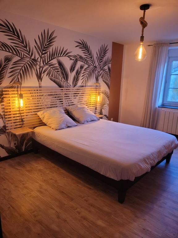 um quarto com uma grande cama branca e uma parede de plantas em Maison rénovée au calme em Dannevoux
