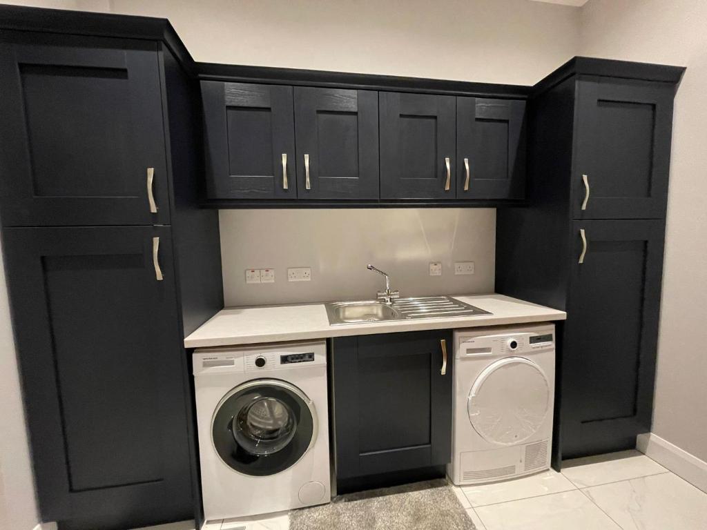 a kitchen with black cabinets and a washing machine at Boutique Villa - Room 1 in Portadown