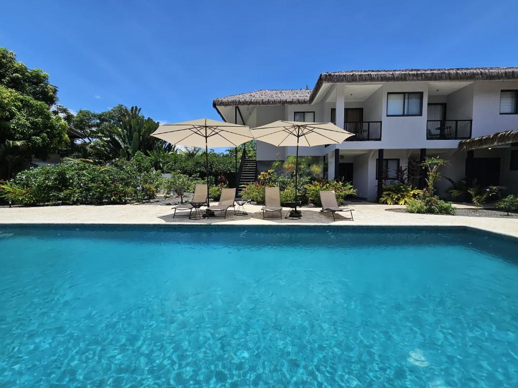 a swimming pool in front of a building with umbrellas at Yuli Hotel in Uvita