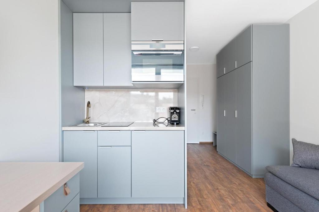 cocina con armarios blancos y sofá en Schickes All-inklusive Apartmentzimmer by RESIDA Asset GmbH, en Brunn am Gebirge
