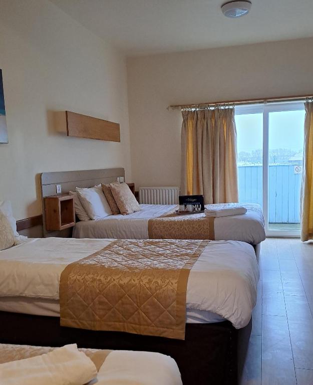 a hotel room with three beds and a large window at Villager Hotel, Ingoldmells in Ingoldmells