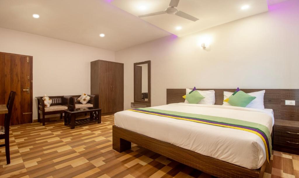 a bedroom with a large bed and a chair at Treebo Trend Elite Plaza 700 Mtrs From Madikeri Fort in Madikeri