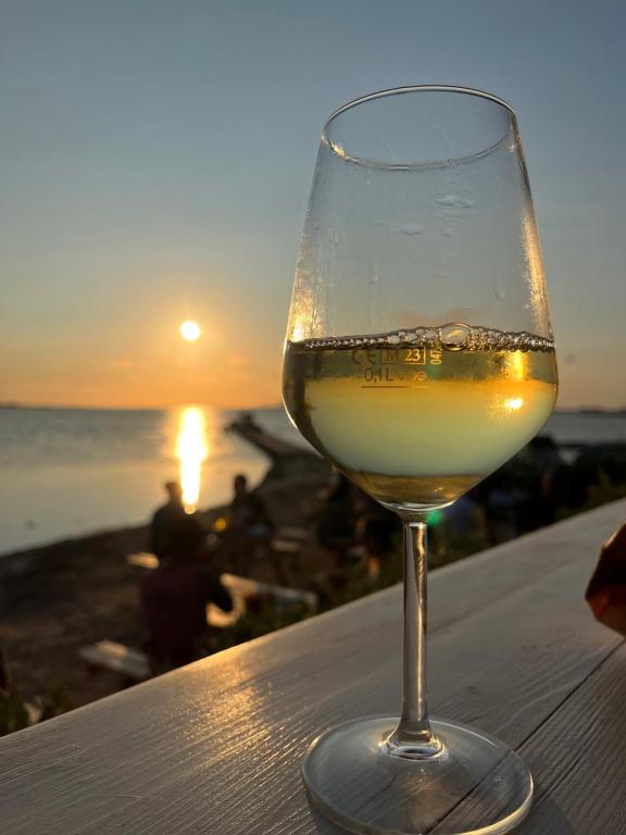 a glass of wine sitting on a table with the sunset at Casa Maria Bartolomeo in Marsala