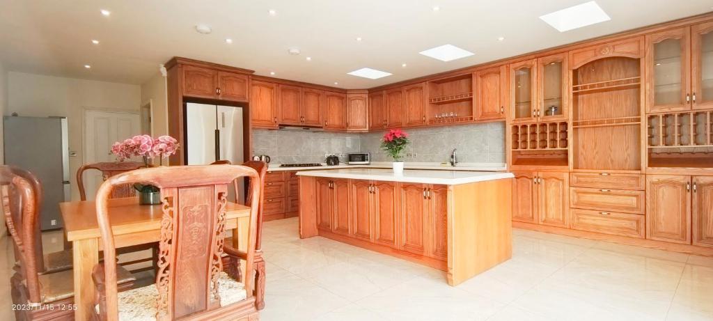 a large kitchen with wooden cabinets and a kitchen island at Aloe Villa in Harrow