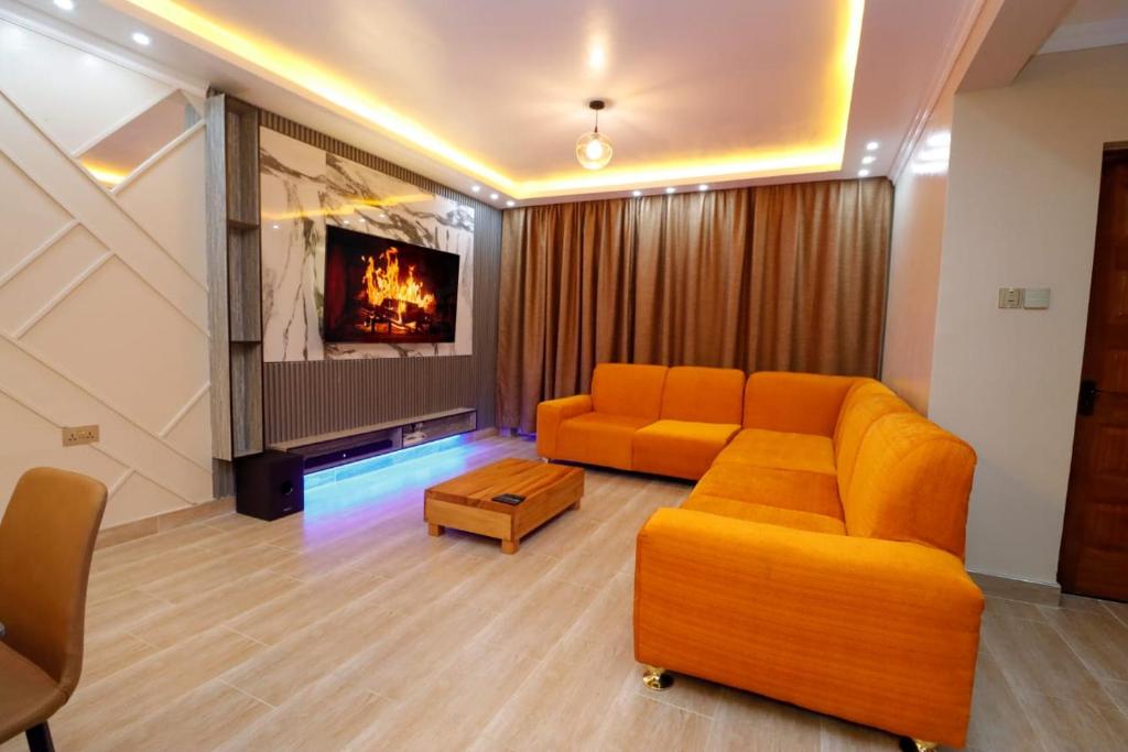 ein Wohnzimmer mit einem orangenen Sofa und einem TV in der Unterkunft Lux Suites Nakuru VIP Suites in Nakuru