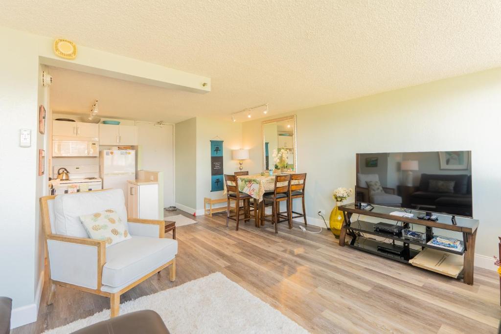 sala de estar con TV grande y cocina en Island Colony 2301 condo, en Honolulu