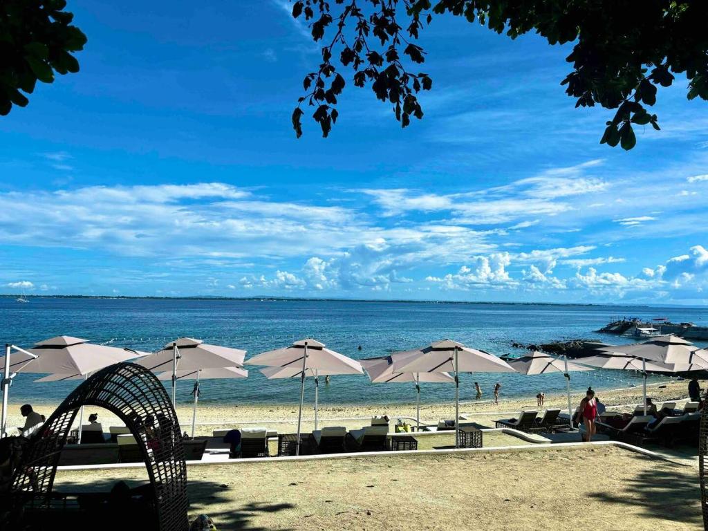 una spiaggia con ombrelloni e persone sulla spiaggia di Cebu Cozy Ocean View 1BR,17th,private beach,pool,Wifi,Mactan a Mactan