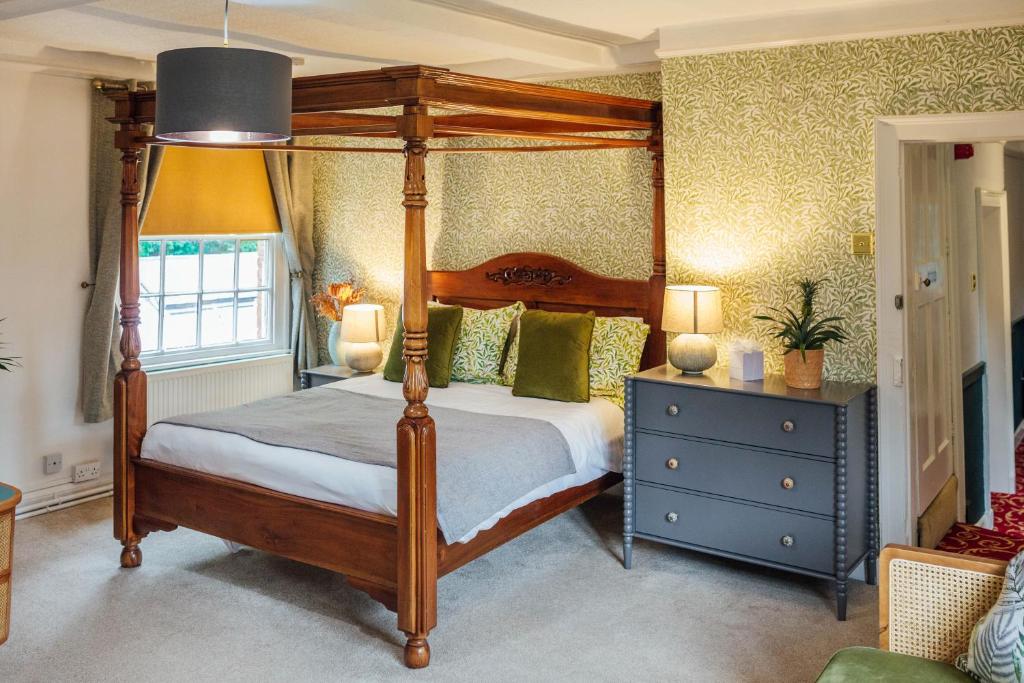 1 dormitorio con cama con dosel y cómoda azul en Old Rectory House & Bedrooms, en Redditch