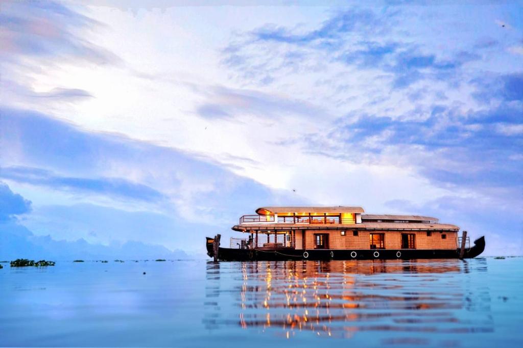 um barco sentado na água sob um céu nublado em IndraprasthamLakeCruise em Alappuzha