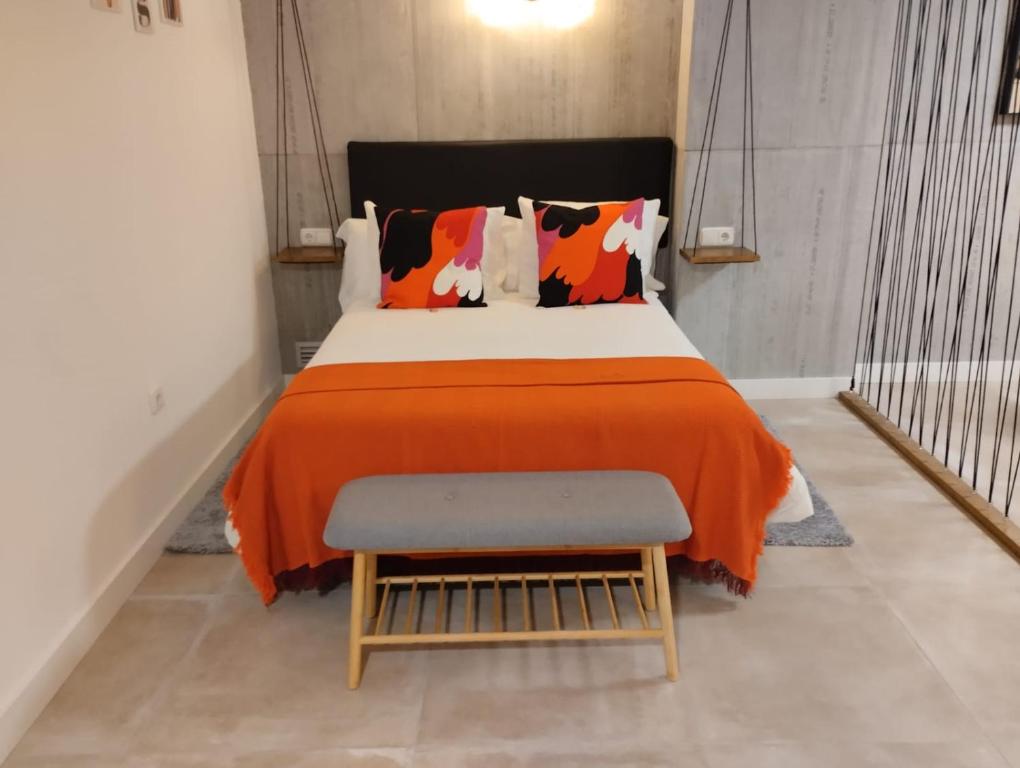 1 dormitorio con 1 cama con manta naranja y taburete en Underground SINTRA experiencia, en Almansa