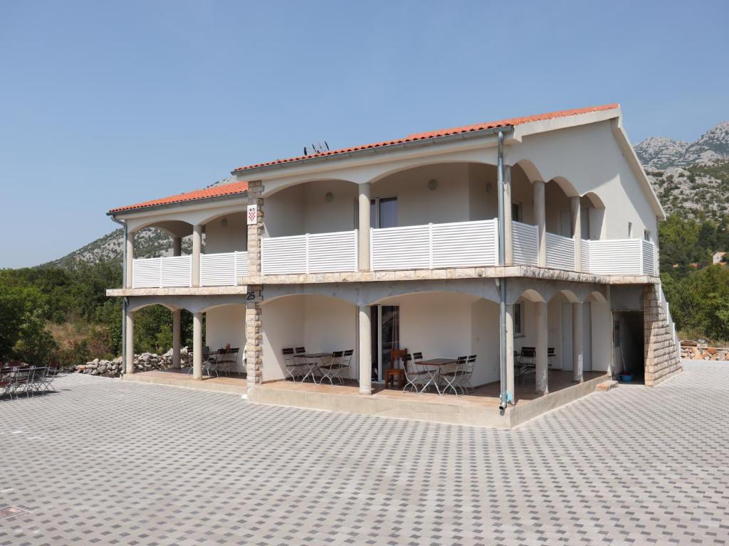 a large white building with a balcony and tables at Bajic Apartmani in Seline